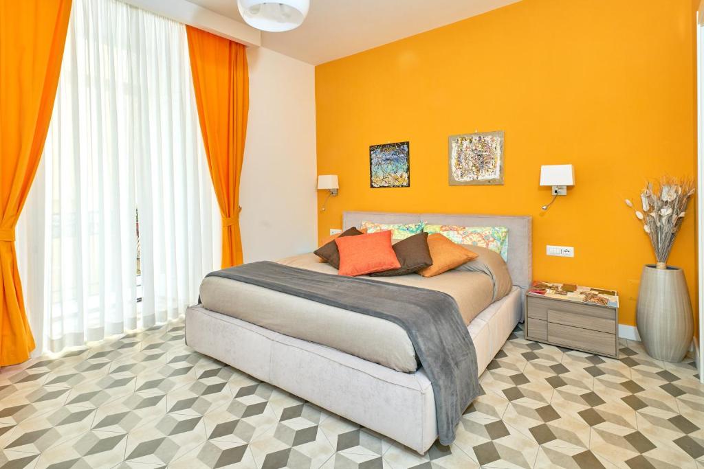 ein Schlafzimmer mit einem Bett mit einer orangefarbenen Wand in der Unterkunft A Casa del Principe LT in Neapel