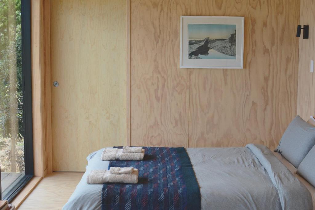 een slaapkamer met een bed met handdoeken erop bij The Huts in Ahipara