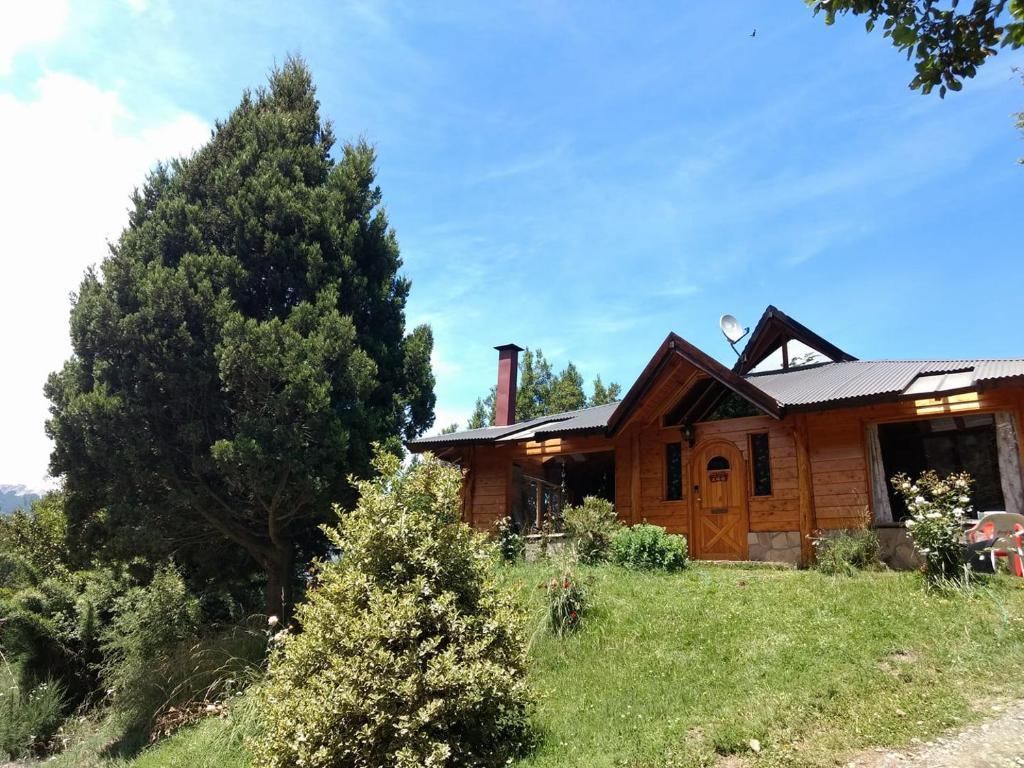 una casa de madera con un árbol delante de ella en Lo De Pablo en Villa La Angostura