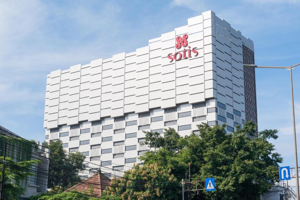 a large white building with a sign on it at Sotis Residence Pejompongan in Jakarta