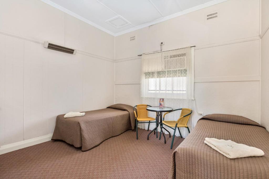 a room with two beds and a table and chairs at Centennial Hotel Gulgong in Gulgong