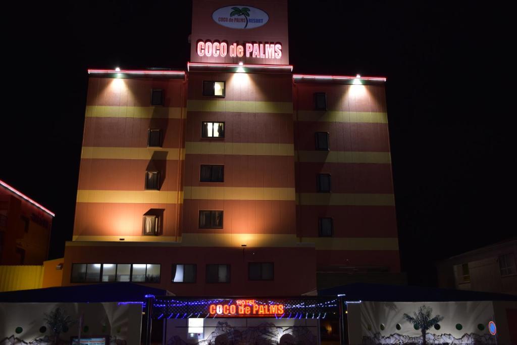ein Gebäude mit einem Schild darüber in der Nacht in der Unterkunft Hotel Coco de Palms & Mer (Love Hotel) in Ōita