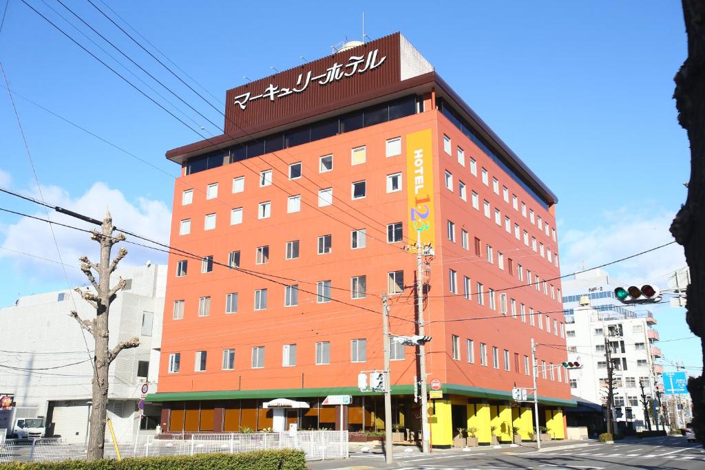 ein hohes rotes Gebäude mit einem Schild darüber in der Unterkunft Hotel 1-2-3 Maebashi Mercury in Maebashi