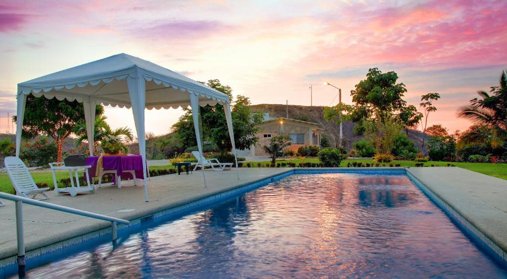 a pool with a gazebo and a table and chairs at Saint Patricks Lodge in Santa Elena