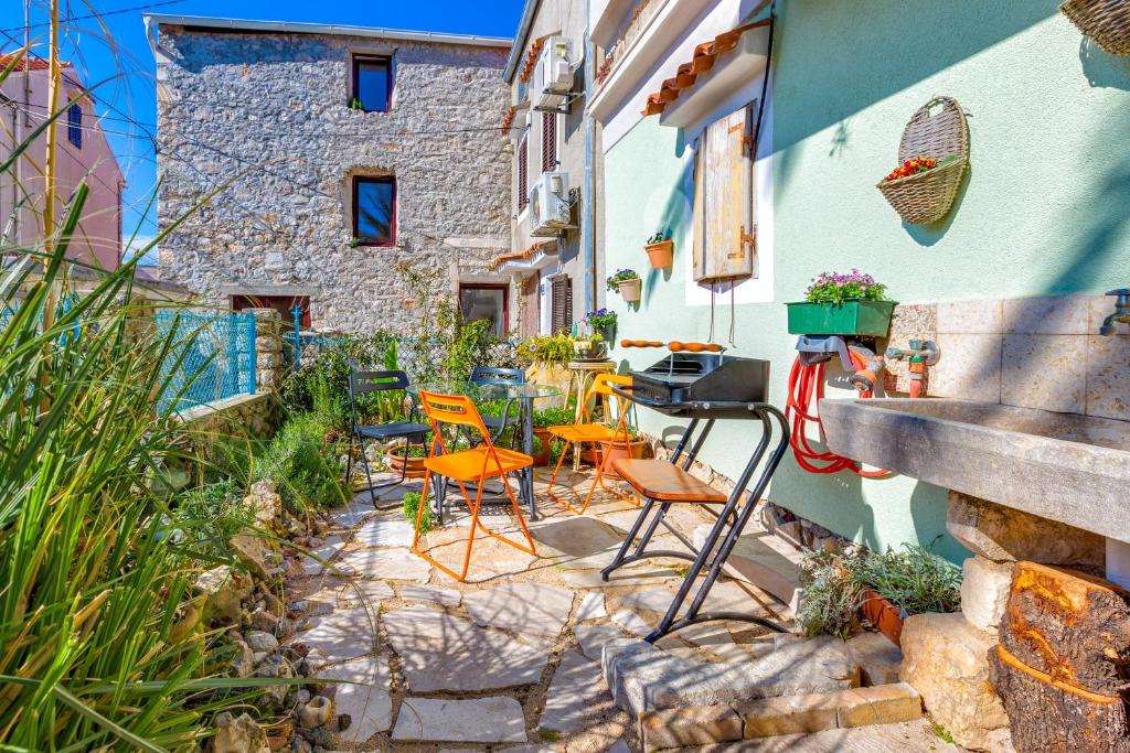 un patio con sedie e tavoli e un edificio di Apartment Tempo Colorato a Mali Lošinj (Lussinpiccolo)