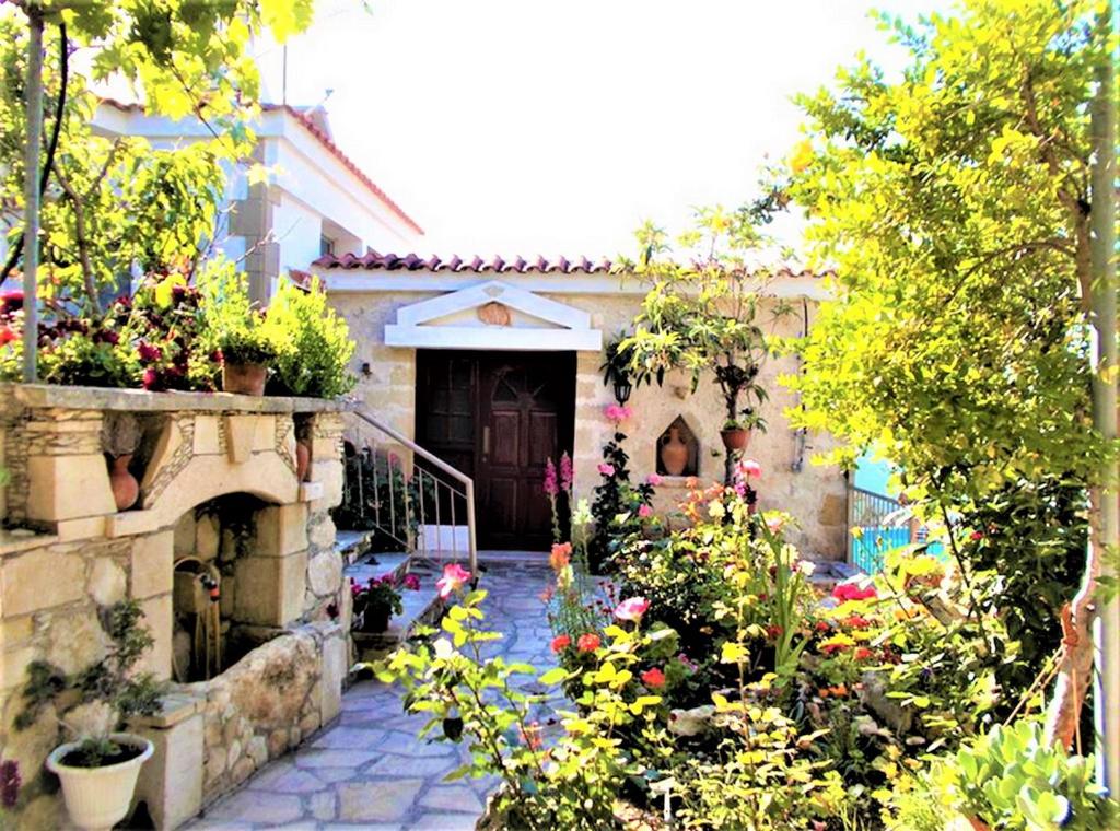 a house with a garden with flowers in front of it at Rose Garden Villa Peristerona in Peristerona