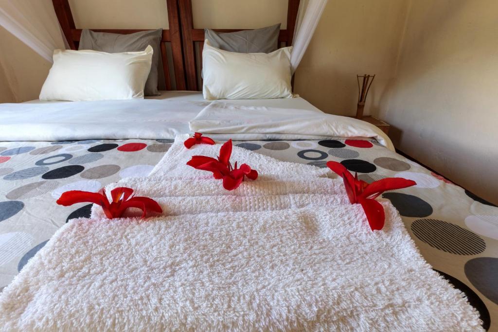 a bed with red flowers on top of it at Gorilla Valley Lodge in Bwindi Impenetrable Park