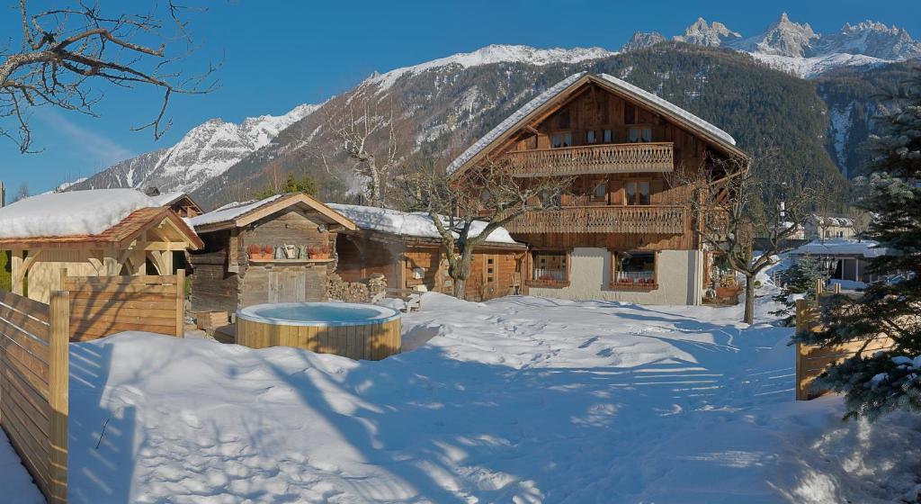 a log cabin in the snow with mountains in the background at Auberge du Manoir in Chamonix