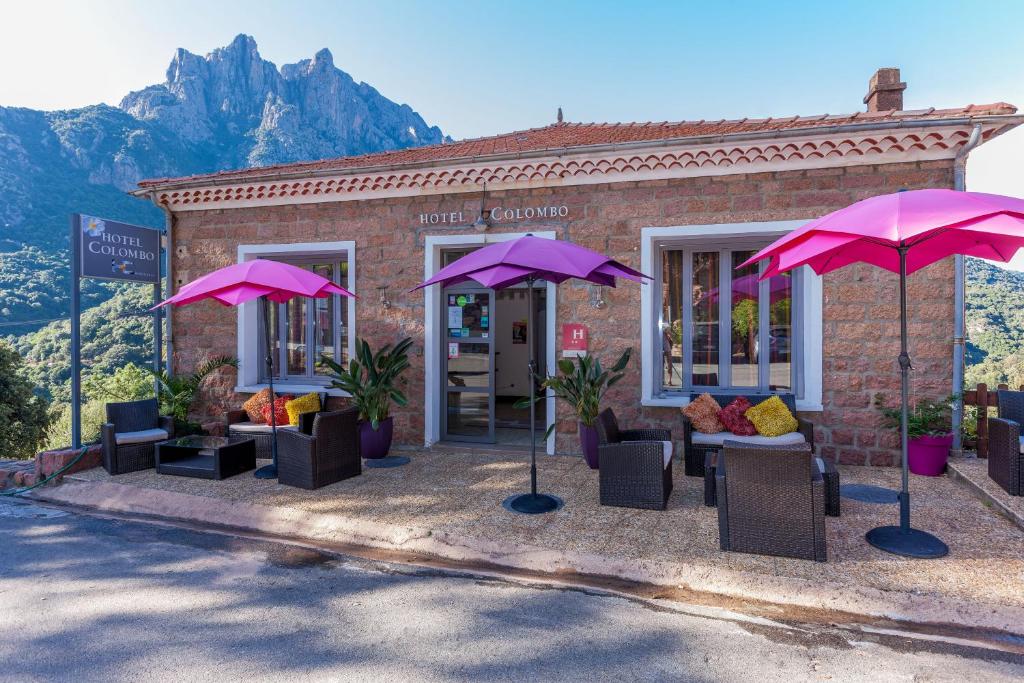 un bâtiment avec des chaises et des parasols en face de celui-ci dans l'établissement Hôtel Colombo- Porto Corse, à Porto Ota