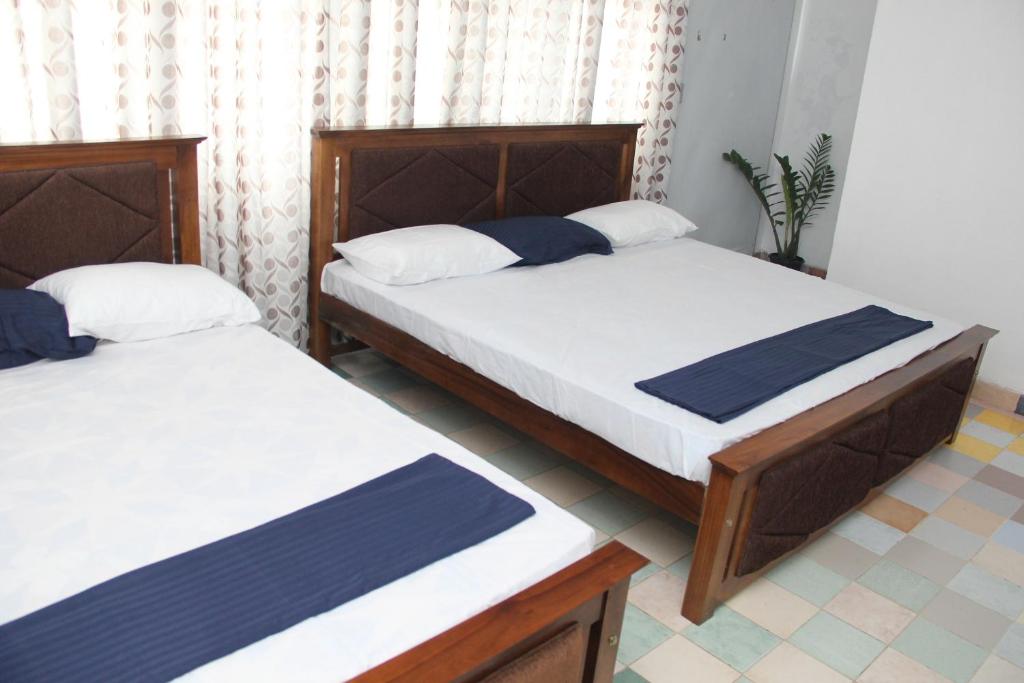 Duas camas num pequeno quarto com os melhores detalhes em Kingfisher Hostel em Anuradhapura