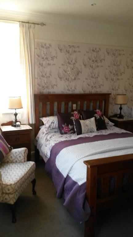 a bedroom with a large bed and a chair at Ashbourne House in Sheringham