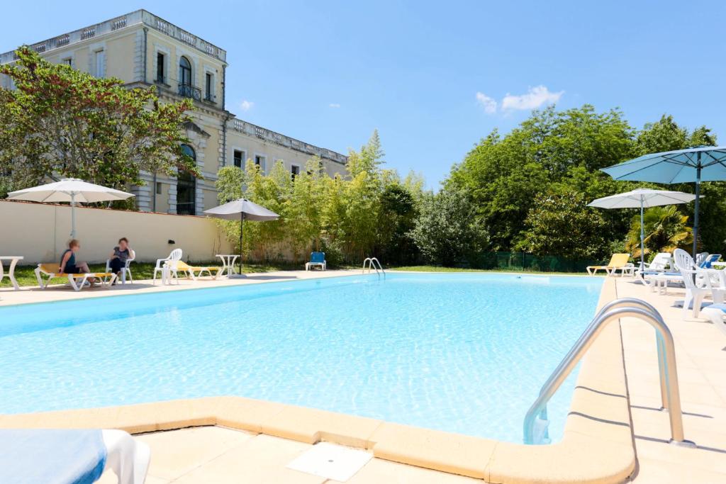 a large swimming pool with chairs and umbrellas at Résidence du Château de Bégué in Cazaubon