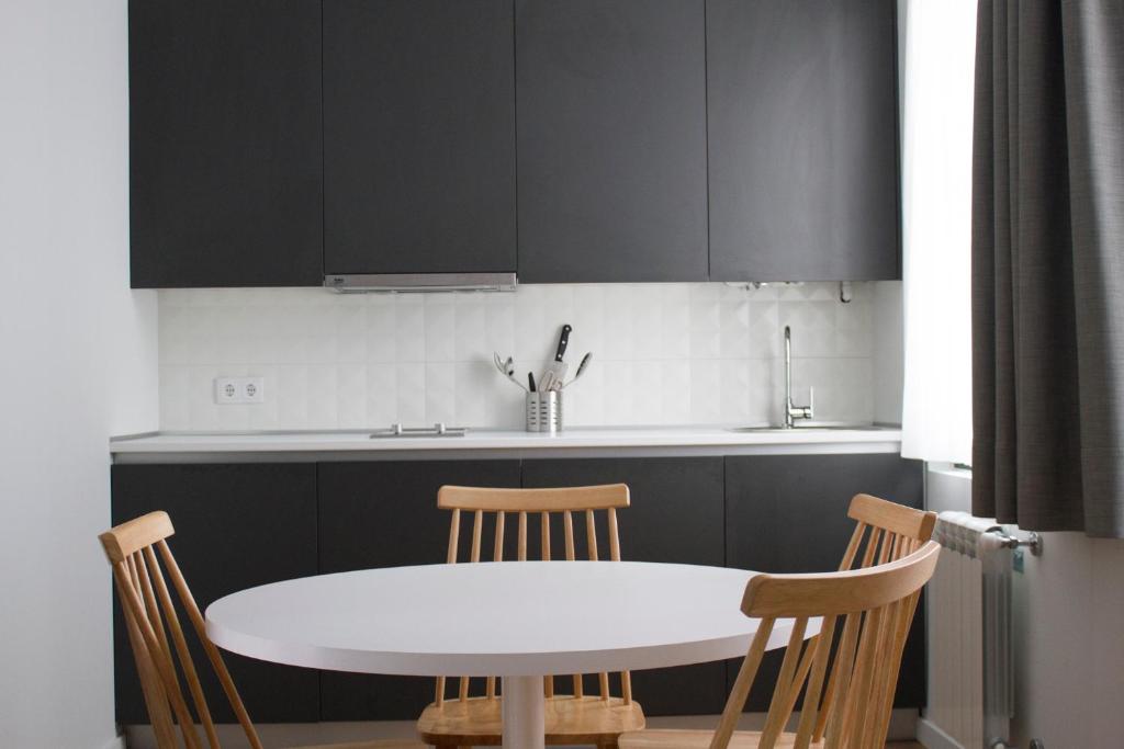 kuchnia z białym stołem i krzesłami w obiekcie Lux Apartamentos Rosalia w Santiago de Compostela