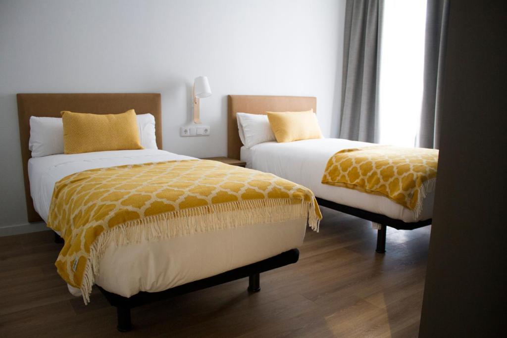 dwa łóżka siedzące obok siebie w sypialni w obiekcie Lux Apartamentos Rosalia w Santiago de Compostela