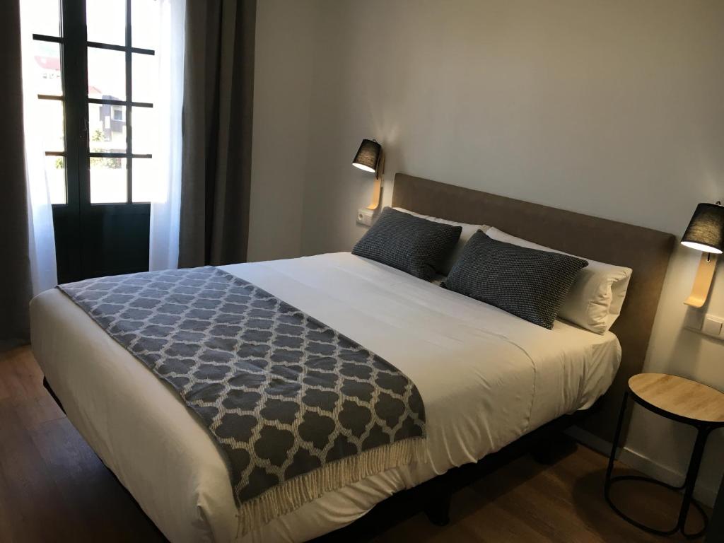 1 dormitorio con 1 cama grande con almohadas azules en Lux Apartamentos Rosalia, en Santiago de Compostela