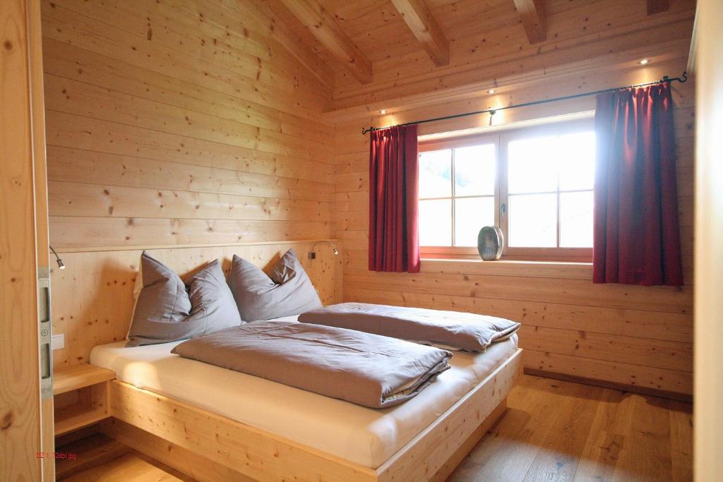 a bed in a log cabin with a window at Almliesl MUEH-512 in Bramberg am Wildkogel
