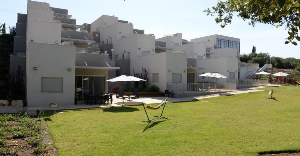 a large white building with umbrellas in a yard at Keshet Eilon - Suites and Villas in Elon