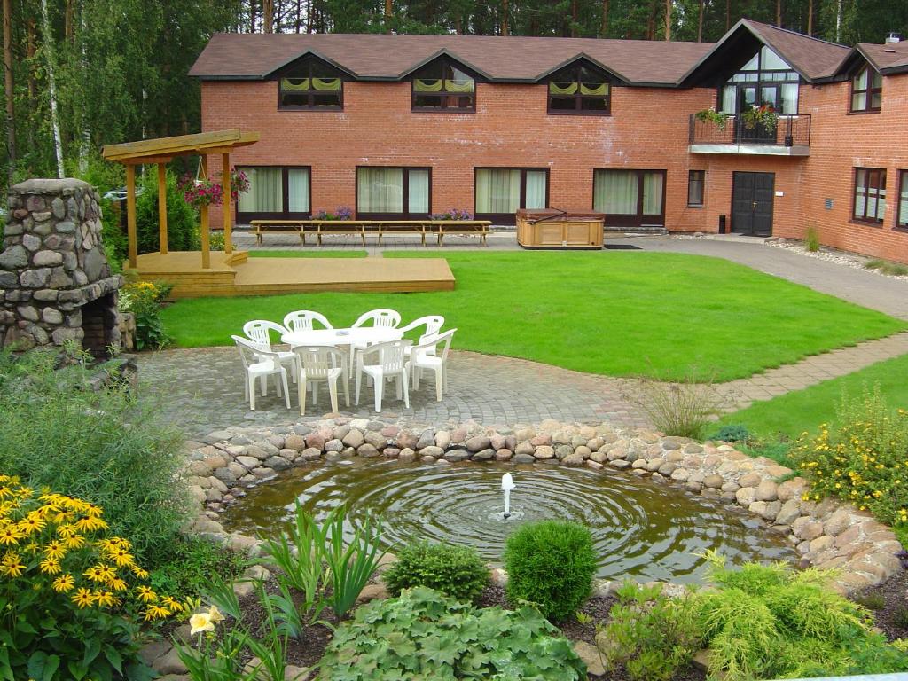 a house with a table and chairs and a pond at Strenči Guesthouse & SPA in Strenči