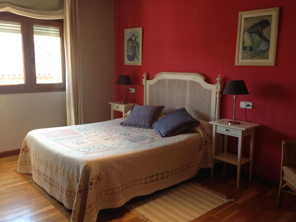 1 dormitorio con 1 cama con paredes rojas y 2 mesas en Apartamento Puerto De Llanes, en Llanes