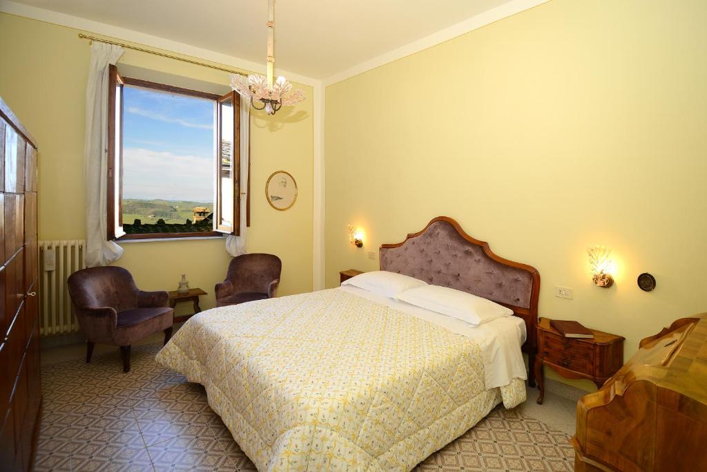 1 Schlafzimmer mit einem Bett, 2 Stühlen und einem Fenster in der Unterkunft Residenza Savonarola Luxury Apartment in Montepulciano
