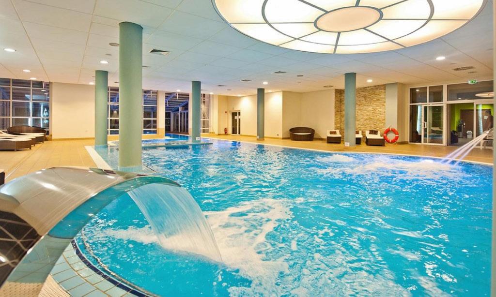 a large pool with a water slide in a building at Diva Resort in Kołobrzeg