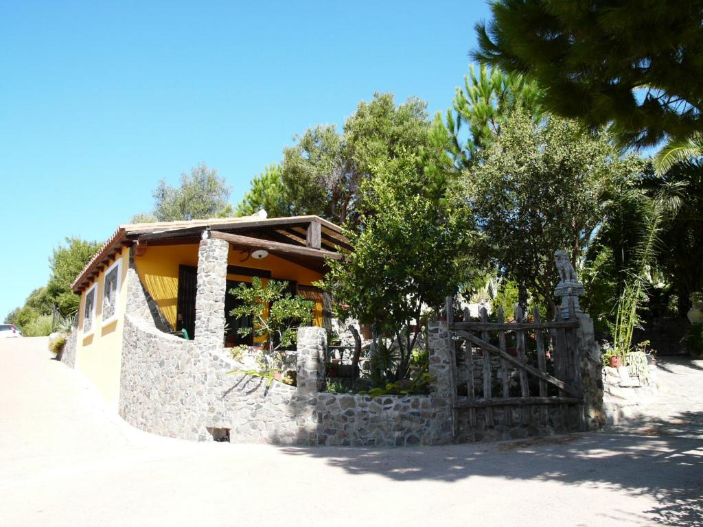 une maison avec un mur en pierre et un portail en bois dans l'établissement B&B IL GIARDINO, à Arbus