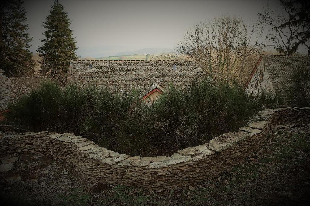a garden with a stone fence and plants at Domaine des Maréquiers chambre Pimprenelle in Saint-Germain-du-Teil