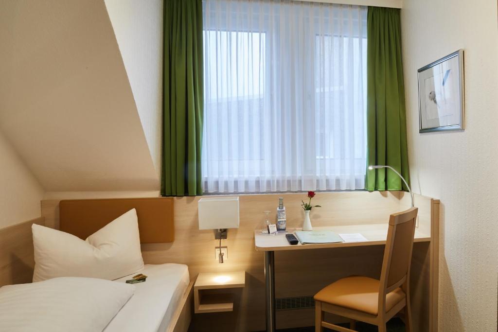 a hotel room with a bed and a desk and a window at Hotel Zur Traube in Velbert