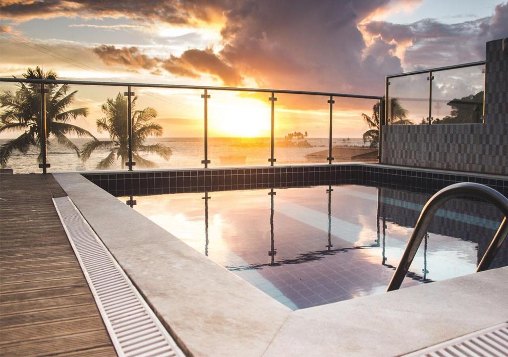 a swimming pool on top of a building with a sunset at Pousada Ilha do Sol in Morro de São Paulo