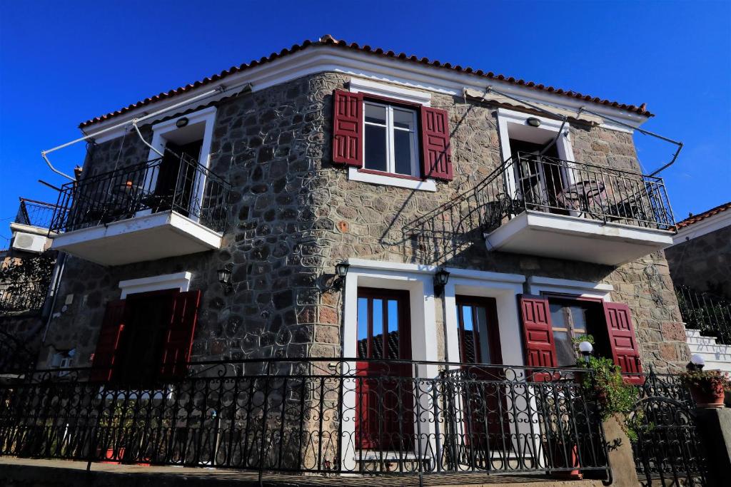 ミティムナにあるNianthi Apartmentsの赤いドアとバルコニー付きの石造りの家