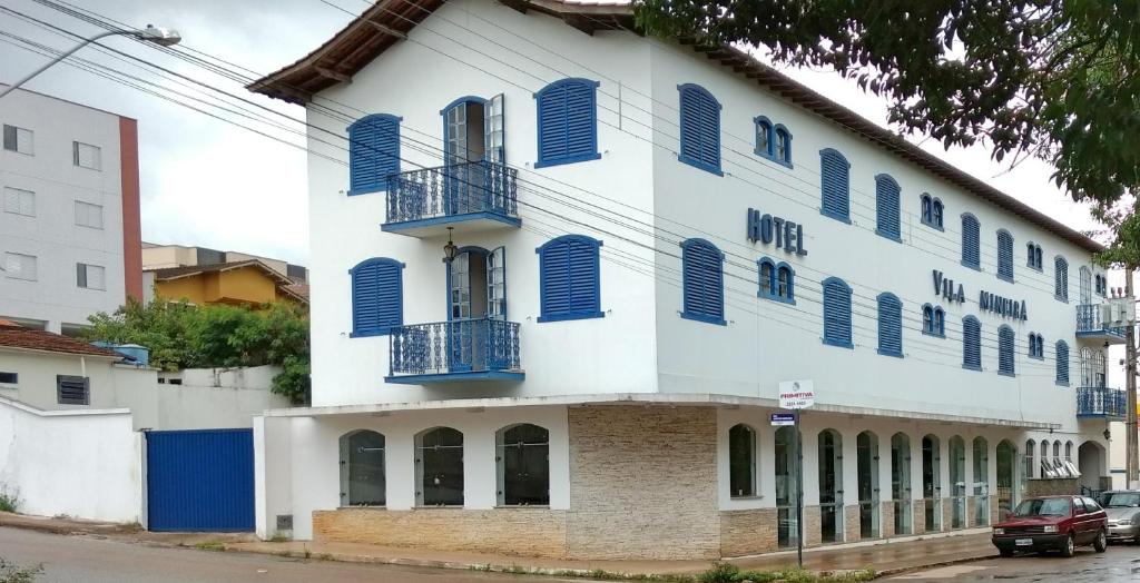 a white building with blue shutters on it at Hotel Vila Mineira in Oliveira