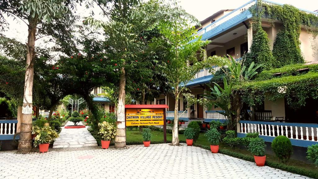 un edificio con árboles y plantas delante de él en Chitwan Village Resort, en Sauraha