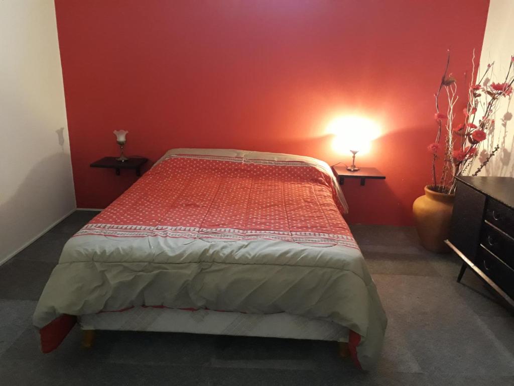 1 dormitorio con 1 cama con pared roja en Alquiler Monoambiente in 
