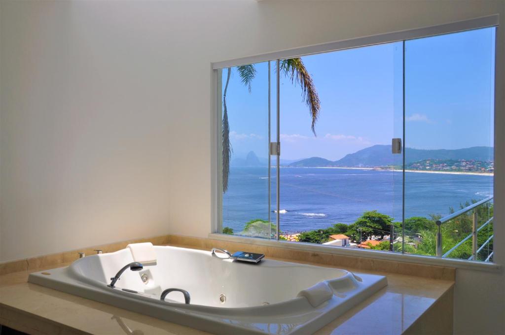 un bagno con vasca e ampia finestra di Marina's Praia Itaipu a Niterói