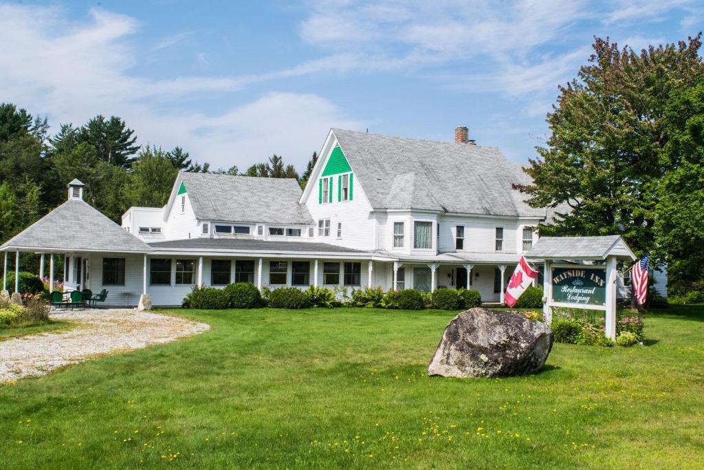 una gran casa blanca con una roca en el patio en The Wayside Inn en Bethlehem