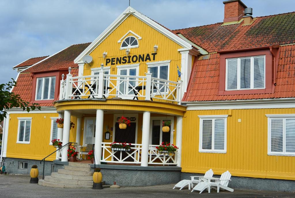 ein gelbes Gebäude mit einem Balkon auf dem Dach in der Unterkunft Pensionat Åsgården in Lyrestad