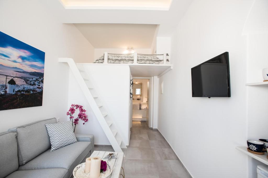 a living room with a couch and a tv at Christy Suites by Alpha Living in Mikonos