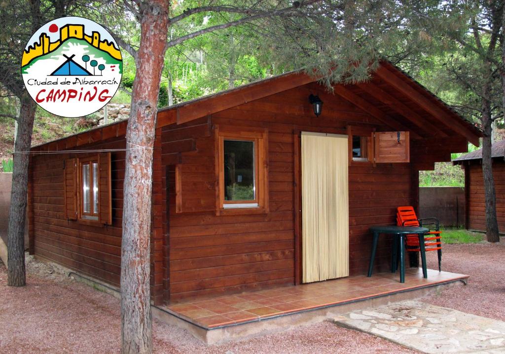 Cabaña de madera pequeña con mesa y taburete en Camping-Bungalows Ciudad de Albarracín, en Albarracín