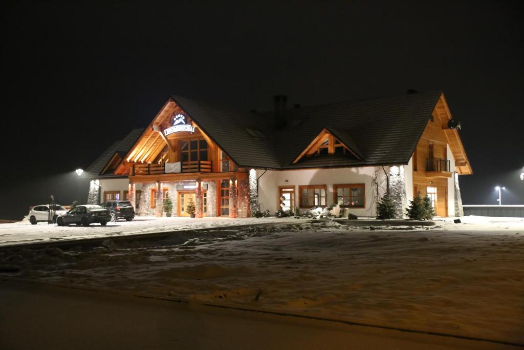 una gran casa de madera en la nieve por la noche en Dwór Kukuczka, en Istebna