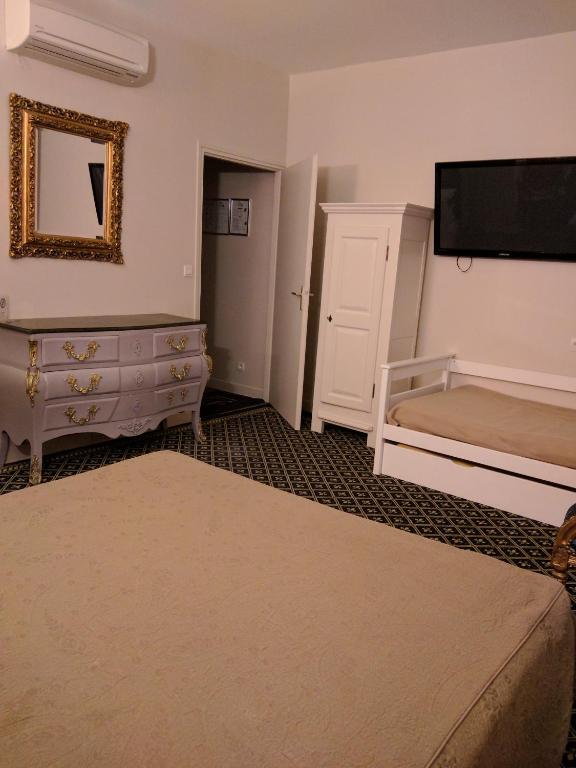 - une chambre avec un lit, une commode et une télévision dans l&#39;établissement Hotel Fleur de Lys, à Bailleul