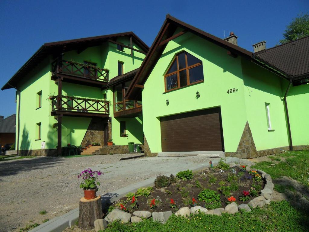ein grünes Haus mit einer Garage und einer Auffahrt in der Unterkunft Leniwy Motyl in Rajcza