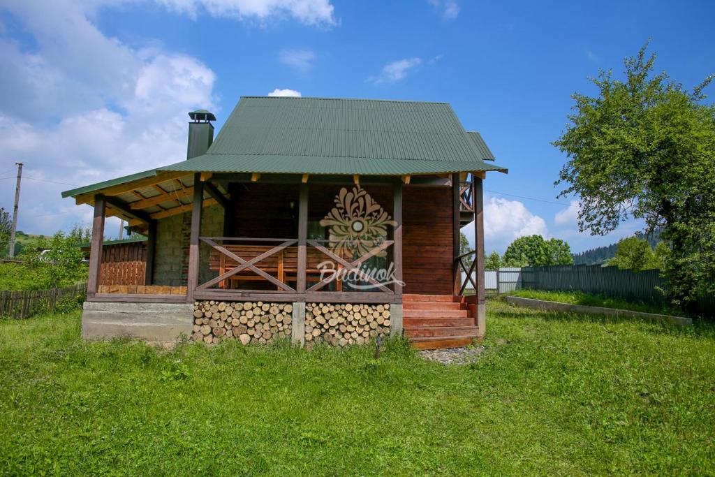 een kleine houten hut met een groen dak bij Котедж "Газда" in Izki