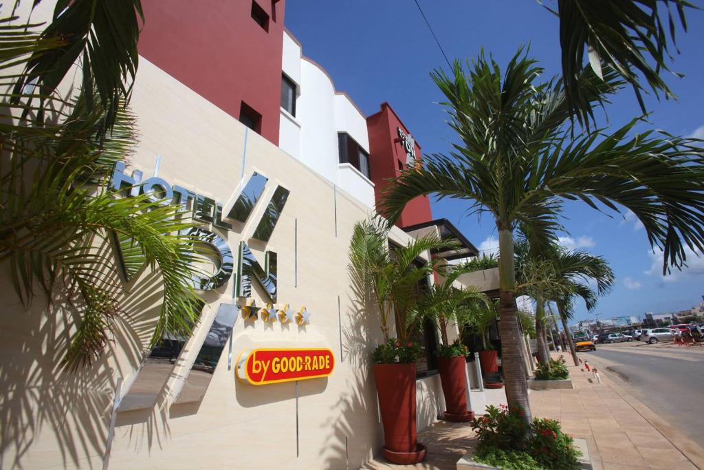 a sign on the side of a building with palm trees at Hotel VDN by Good Rade in Dakar