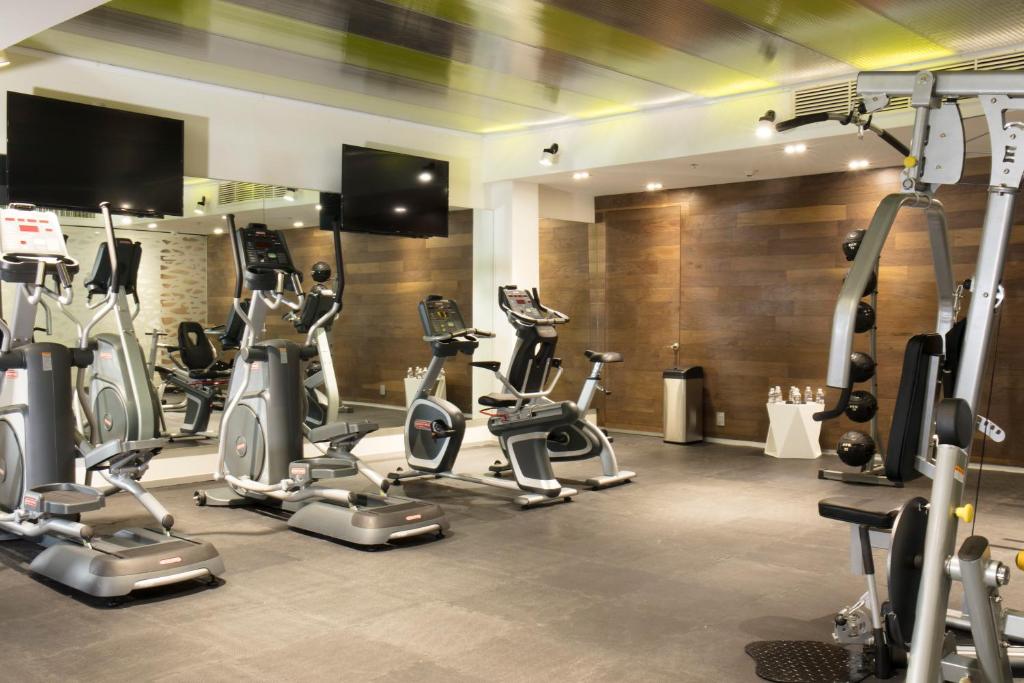 A compact fitness room with treadmills, elliptical trainers, bicycles and a cable machine.