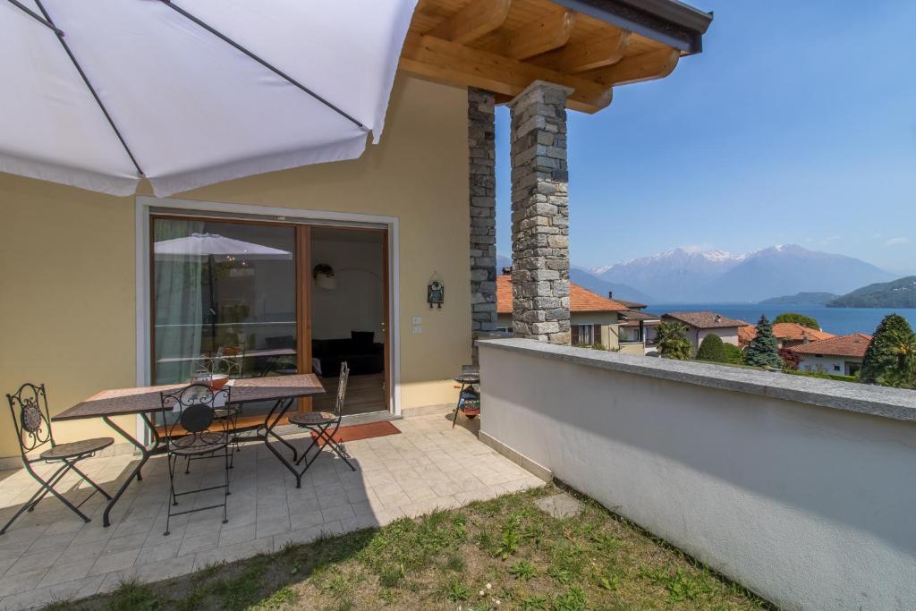 une terrasse avec une table, des chaises et un parasol dans l'établissement Magnolia Musso Vista, à Musso