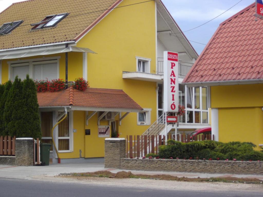 a yellow building with a sign for a hotel at Szieszta Panzió in Sárvár