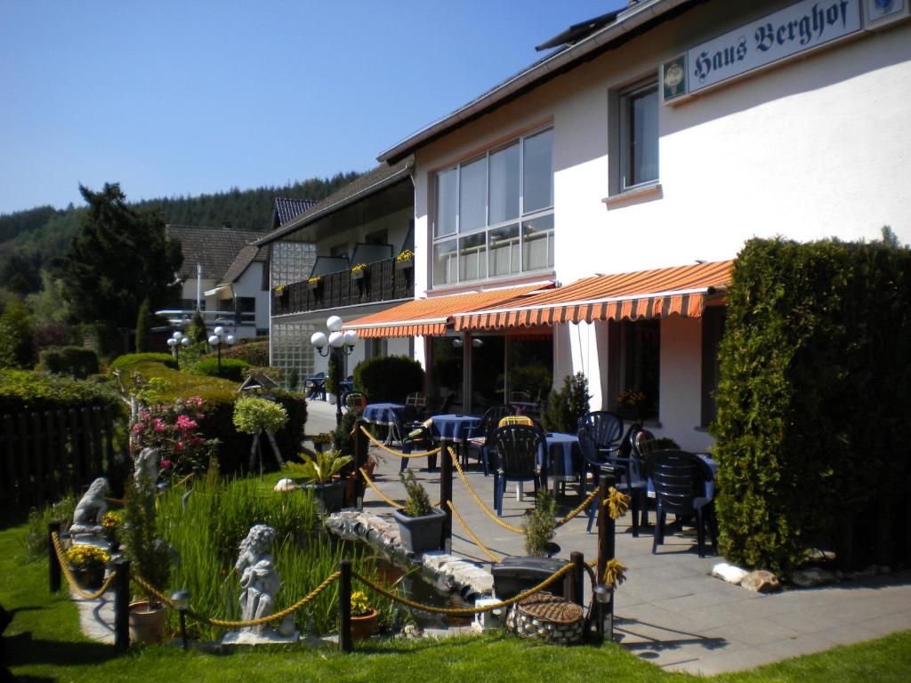 ein Gebäude mit Stühlen und Tischen davor in der Unterkunft Hotel Pension Haus Berghof in Hellenthal