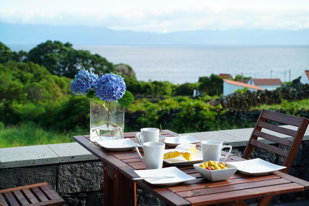 Casa do Cedro do Mato في Terra Alta: طاولة خشبية مع طعام و مزهرية مع الزهور الزرقاء