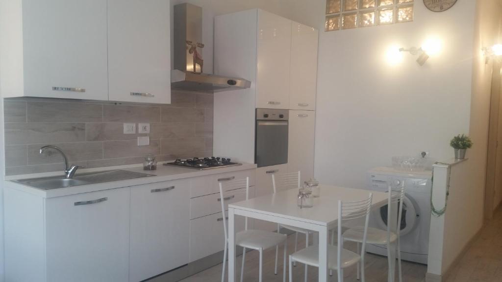 una cucina con armadi bianchi e tavolo e sedie bianchi di Monica's Apartment a Marina di Carrara