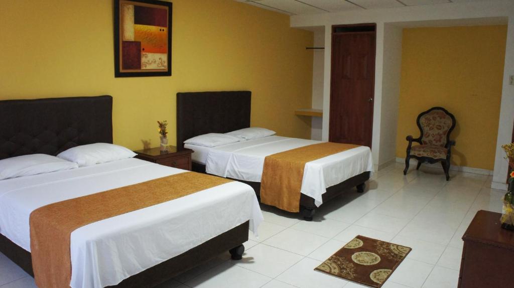 une chambre d'hôtel avec deux lits et une chaise dans l'établissement Hotel Parque del Perro, à Cali